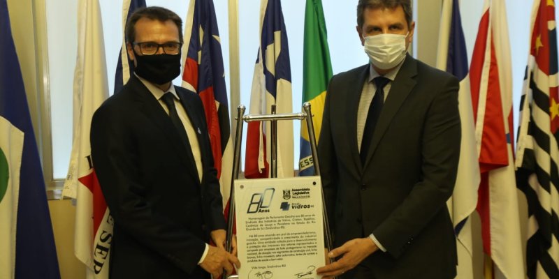 dois homens brancos de máscara seguram uma placa em homenagem ao Sindividros-RS