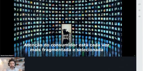 Diversas telas de TV e celulares com informações em fundo preto. No canto esquerdo, abaixo, um quadro com um homem com barba, de camisa branca e com microfone